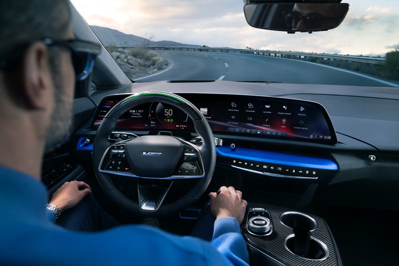 Front View of the 2026 OPTIQ-V Driving Through the Dusk Utilizing its Headlights | Bayway Cadillac of The Woodlands in The Woodlands TX