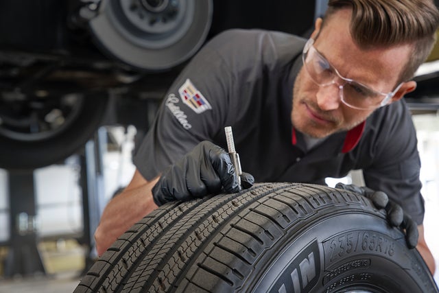 A technician checking the tread of a tire.