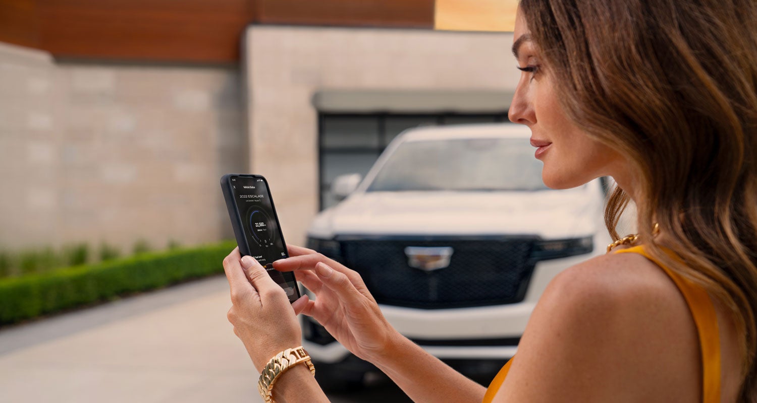 lady checking her mobile with a Cadillac vehicle background | Bayway Cadillac of The Woodlands in The Woodlands TX