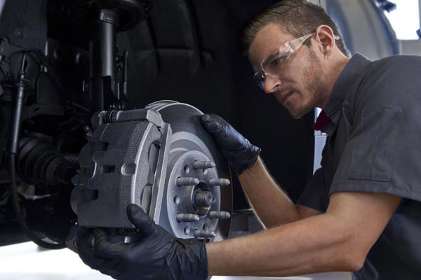 Service technician checking the rotor and brake pads on a vehicle
